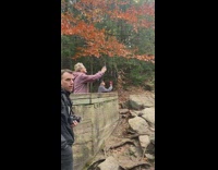 Man shirtless handstand pose on the rock near the river