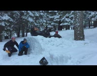 guys on snow tube sliding down hill and hitting tree