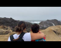 Family at rock shore splashed by waves