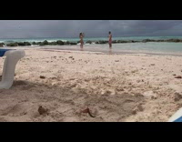 Man smokes cigar while woman takes his picture at the beach