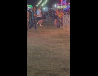 Woman in yellow tube top leans on the carnival railings