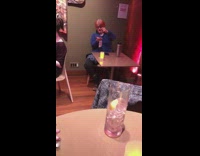 Woman blue jacket holds out hand and swings necklace at restaurant table