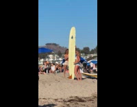 Two women in bikini poses with surfboard