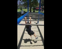Little kid black shirt monkey bars face plants into sand woodchips