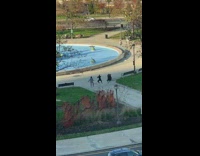 Three people dance near park pond dinosaur statues