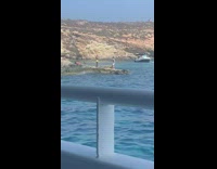 Guy black white shirt dance on rock beach
