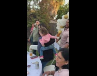 Guy pulls chair away from pregnant woman birthday party