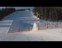 Skier rides fast down slope, does a big jump off ramp and lands