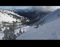 Guy on snowmobile riding off high cliff in snowy mountain 
