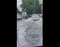 White car driving on a completely flooded street 
