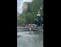 Shirtless man sombrero walk around water fountain