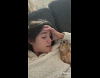 Orange cat laying on owners chest staring at her 