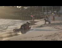 woman lays on mans back at beach photo shoot arms out