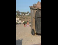 Girl red bikini kneel sand trash bin