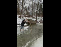 Boy uses stick to go over frozen river 