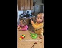 Girl records little sister eating food at table
