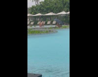 Woman in bikini yoga pose at the pool while it rains