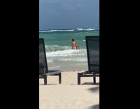 Two guys jump avoid big waves beach