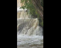 Woman swings off tree branch into waterfall