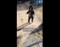 Woman laughing at son slipping on sidewalk