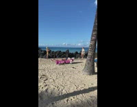 Woman in bikini cover up poses on the beach rocks
