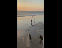 Black sweater guy holds skateboard beach sand 