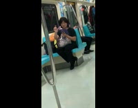 Woman shakes her index finger while using purple phone on the subway 