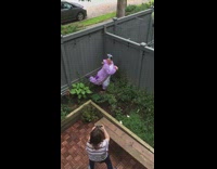 Purple unicorn onesie girl poses planter soil