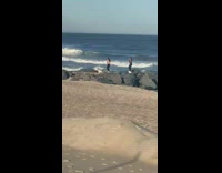 Two girls dance over large rocks beach