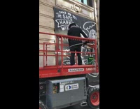 Guy on red platform spray paints wall