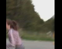 Two girls purple yellow sweatshirts get chased by barking dog down long road