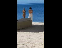 Woman black bikini hands peace sign beach