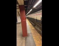 Man in pink thong waits for train at subway station