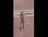 Shirtless guy rainbow leggings spins around courtyard