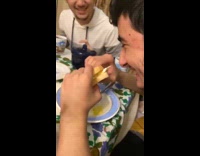 Guy eats sandwich while friends laugh 