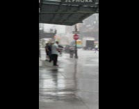 Man waters with host along street while rains 