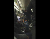Man climbs on wall and holds onto rail while dancing to music on subway train