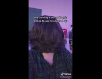 Guy glasses in purple light room laughing brushed long hair down