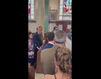 Groom walking down aisle turns to ask friend question 
