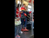 Woman in Captain Marvel costume with black bag on subway train