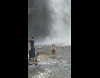 A woman poses in front of a waterfall