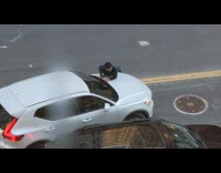 Guy lying down on hood of car as it drives off