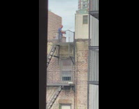 Blue shirt guy shoots bow arrow rooftop 