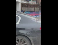 Grandpa bends and squats on sidewalk 