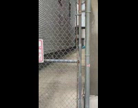 Skeleton sleeps on blue beach chair behind gates in alley