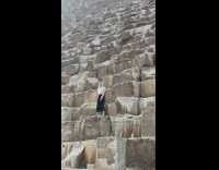 Woman black skirt stands on steps an takes picture on pyramid