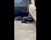 Guy sleeps behind car parked on road