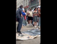 Man paints on street photographed by woman