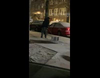Guy dragging heavy metal box on icy sidewalk