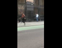 Man with tall long feather on forehead dances on sidewalk